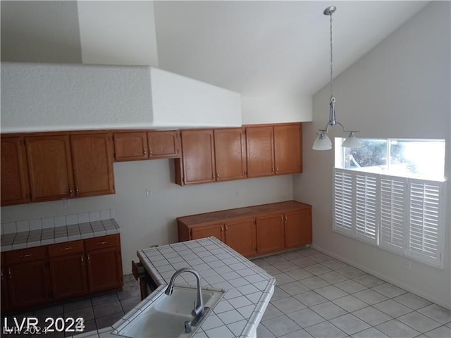 kitchen with vaulted ceiling, tile countertops, sink, pendant lighting, and light tile floors