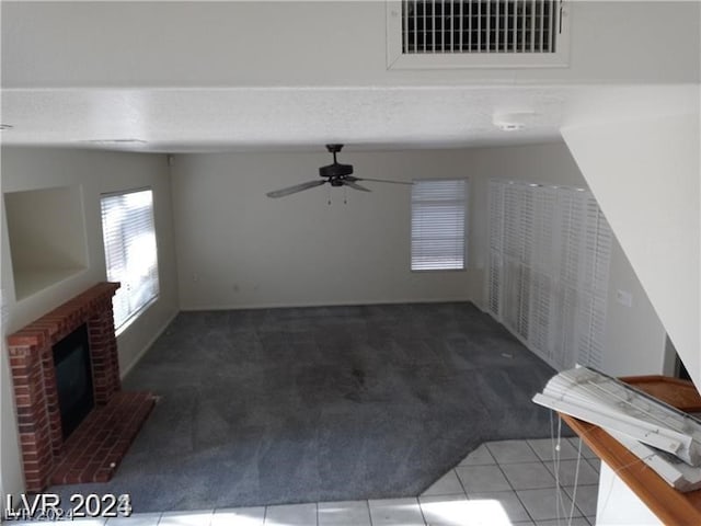 unfurnished living room featuring carpet flooring, a brick fireplace, and ceiling fan