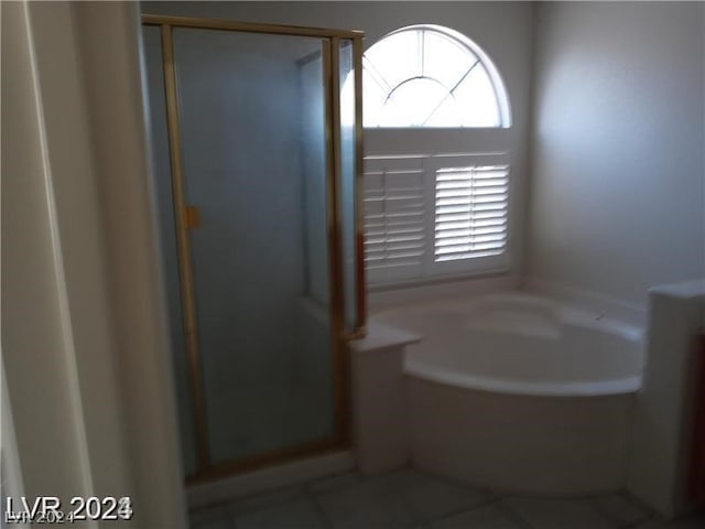 bathroom featuring tile flooring and separate shower and tub