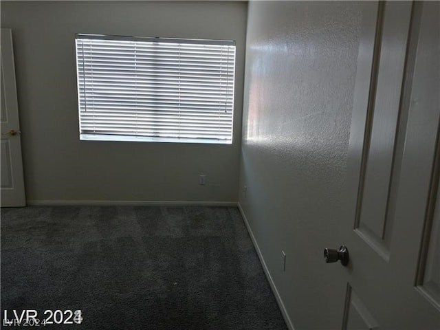 unfurnished room with dark colored carpet and a healthy amount of sunlight