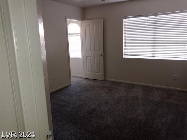 unfurnished room featuring dark carpet