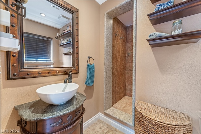 bathroom featuring tile patterned floors, tiled shower, and vanity