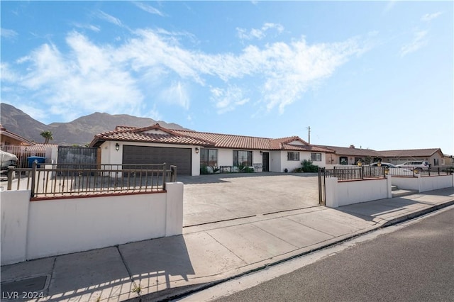 view of front of house with a fenced front yard, a tile roof, a gate, a garage, and concrete driveway