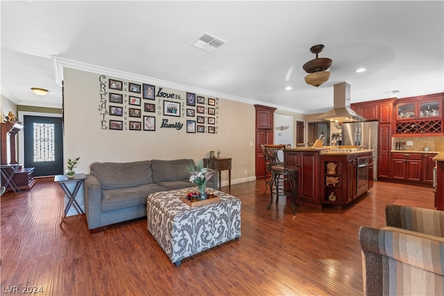 living room featuring bar, ceiling fan, ornamental molding, and dark hardwood / wood-style flooring