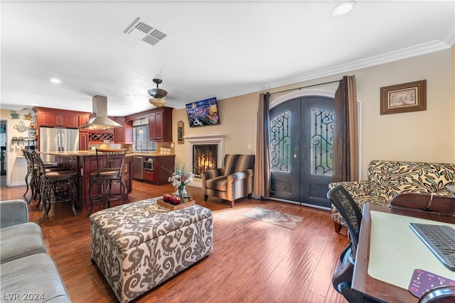 living room featuring dark hardwood / wood-style flooring, ornamental molding, ceiling fan, and french doors