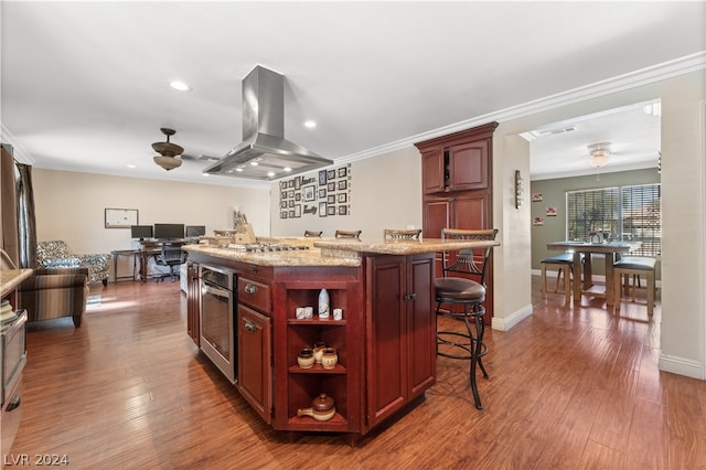 kitchen featuring light stone counters, dark hardwood / wood-style floors, a center island, and island range hood