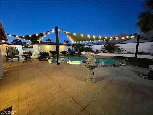 pool at night with a fenced in pool and a patio area