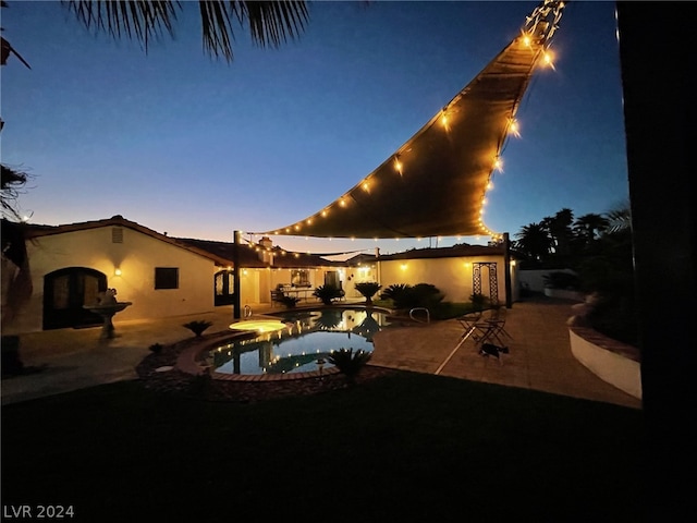 pool at dusk featuring a patio