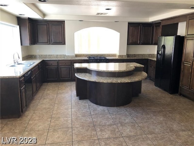 kitchen with a center island, light tile floors, sink, dark brown cabinets, and black appliances