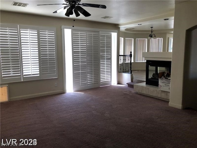 unfurnished living room featuring ceiling fan, a fireplace, and dark carpet