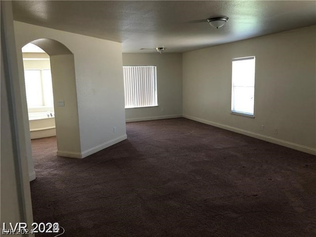 spare room with dark colored carpet