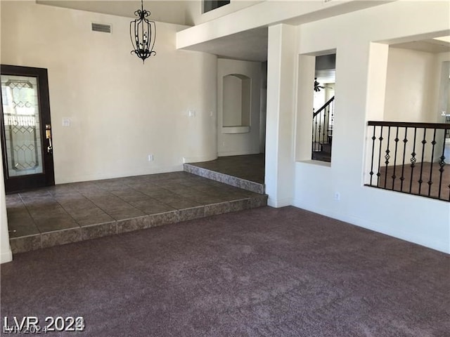 carpeted spare room featuring ceiling fan with notable chandelier