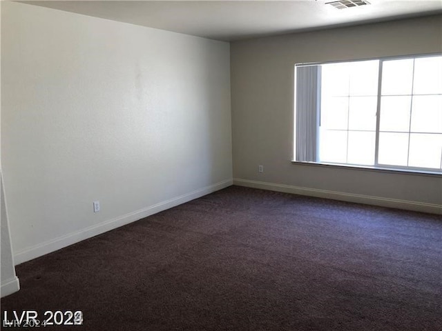 spare room with dark colored carpet