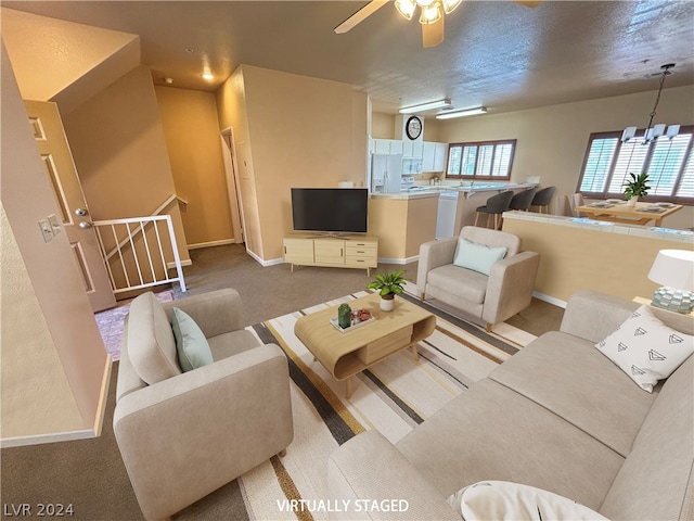 carpeted living room with ceiling fan with notable chandelier