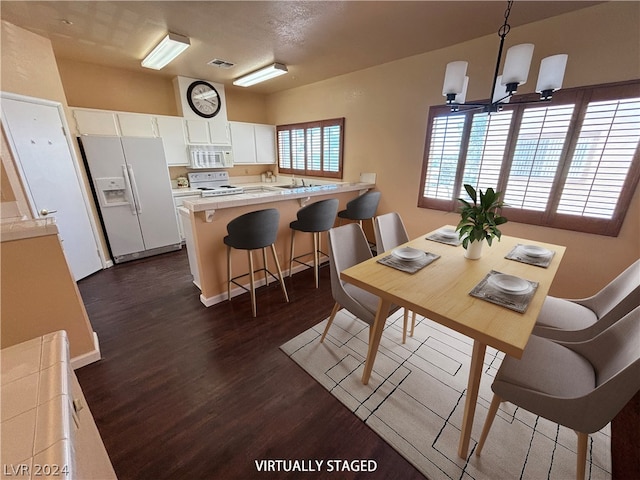 dining space with dark hardwood / wood-style floors and an inviting chandelier