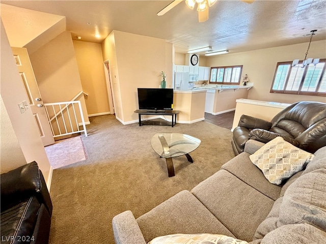 carpeted living room featuring ceiling fan with notable chandelier