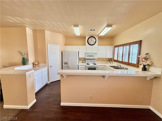 kitchen with sink, white appliances, kitchen peninsula, and dark hardwood / wood-style floors