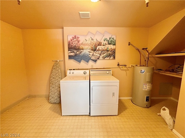 laundry room featuring water heater, washing machine and dryer, and a textured ceiling