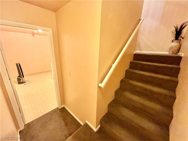 staircase featuring dark colored carpet