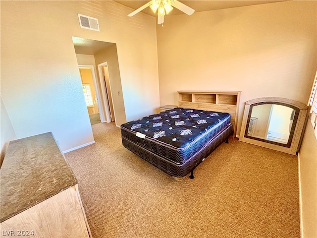 carpeted bedroom with ceiling fan and a high ceiling