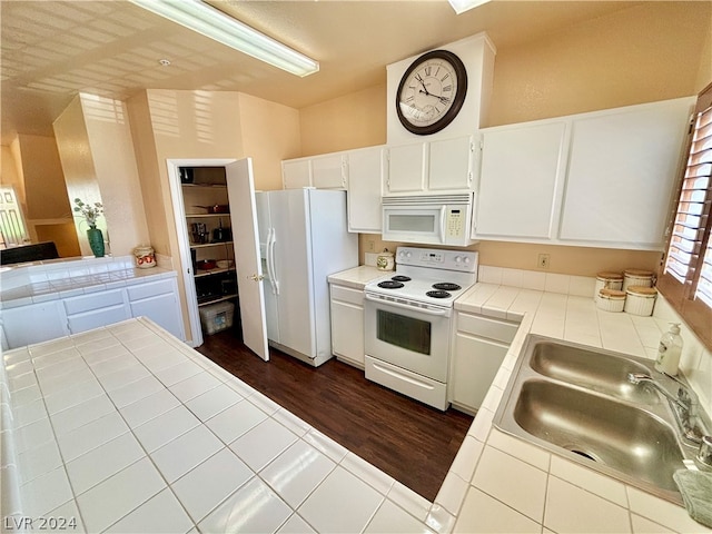 kitchen featuring dark tile floors, sink, white appliances, white cabinetry, and tile counters