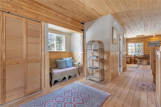 sitting room with wooden ceiling, light hardwood / wood-style flooring, a healthy amount of sunlight, and rustic walls