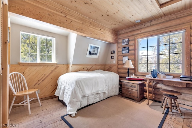 bedroom with wooden ceiling, light hardwood / wood-style flooring, multiple windows, and rustic walls