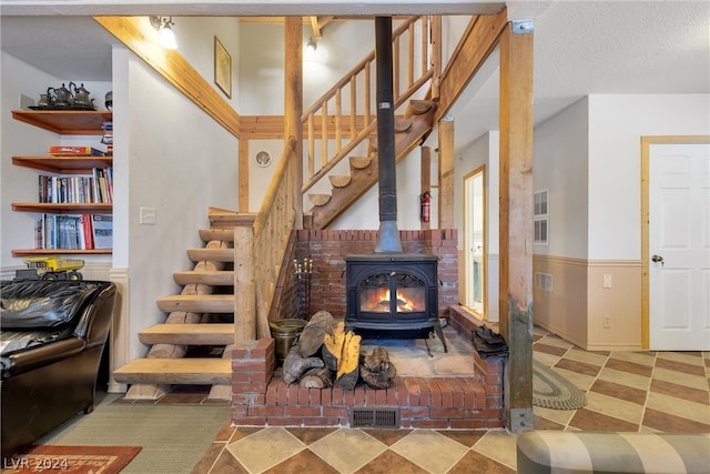 staircase with a textured ceiling, a wood stove, and light tile floors