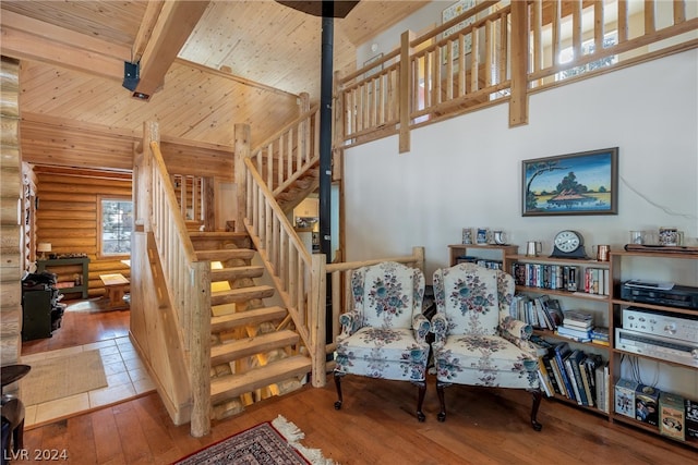 interior space featuring a towering ceiling, light tile flooring, beam ceiling, wooden ceiling, and rustic walls