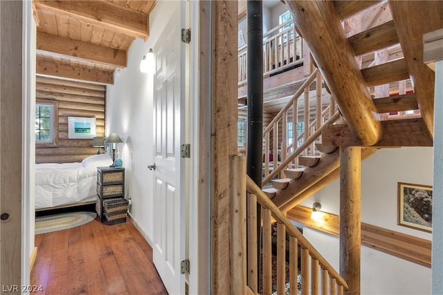 hall featuring wood ceiling, rustic walls, dark wood-type flooring, and beamed ceiling