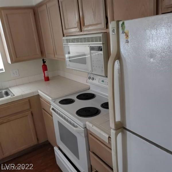 kitchen with dark wood-type flooring, tile countertops, and white appliances