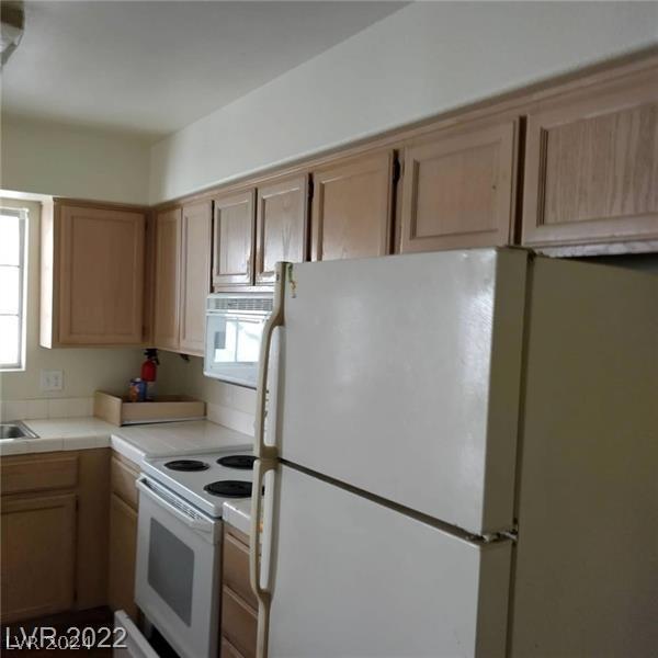 kitchen featuring a wealth of natural light, tile counters, and white appliances