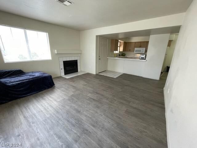 living room with dark wood-type flooring and a tiled fireplace