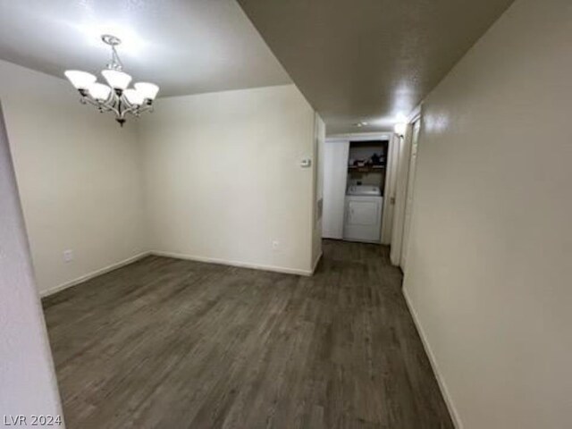 spare room featuring washer / clothes dryer, dark hardwood / wood-style flooring, and a chandelier