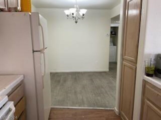 kitchen with white refrigerator, hardwood / wood-style floors, an inviting chandelier, decorative light fixtures, and washer / dryer