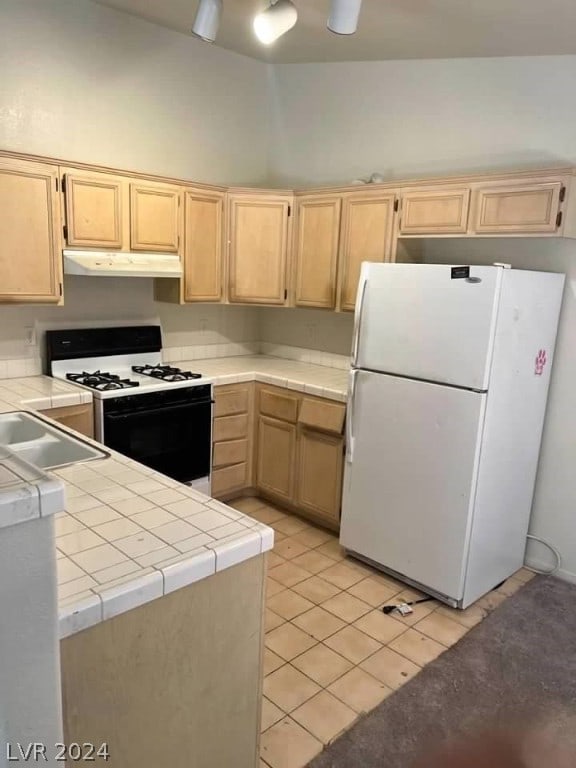 kitchen with white appliances, light tile flooring, light brown cabinets, sink, and tile countertops