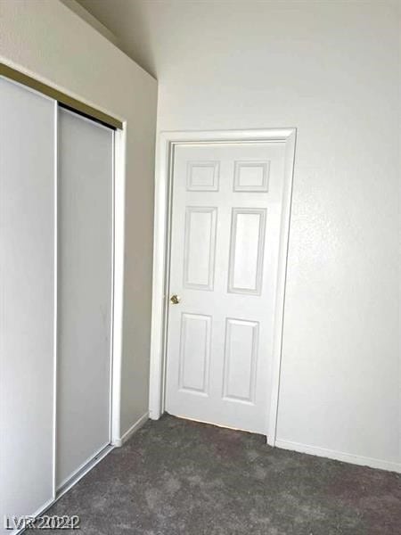 unfurnished bedroom featuring a closet and dark colored carpet