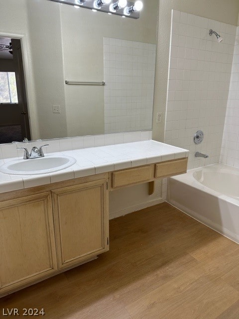 bathroom with wood-type flooring, vanity, and tiled shower / bath combo