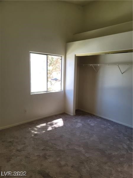 unfurnished bedroom featuring a closet, dark carpet, and a high ceiling