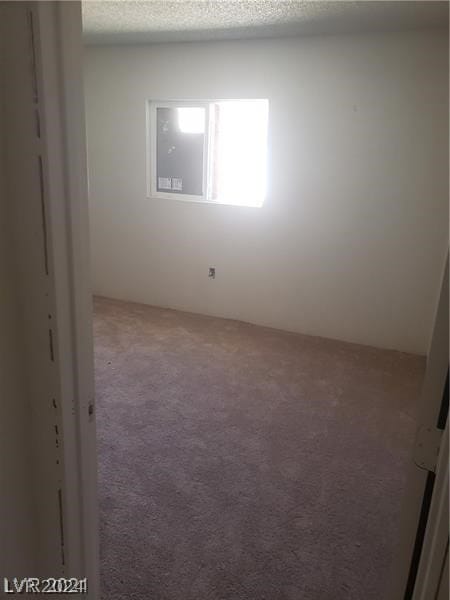 carpeted empty room featuring a textured ceiling