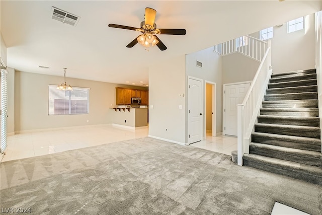 unfurnished living room with plenty of natural light, carpet, and ceiling fan with notable chandelier