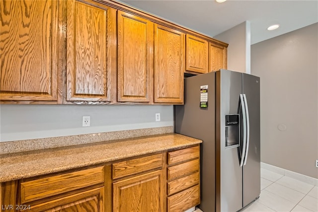 kitchen featuring light stone countertops, stainless steel fridge with ice dispenser, and light tile floors