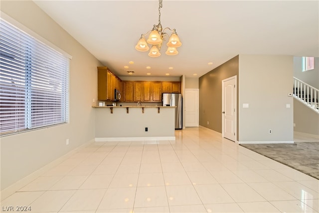 kitchen with hanging light fixtures, an inviting chandelier, light tile floors, and stainless steel appliances