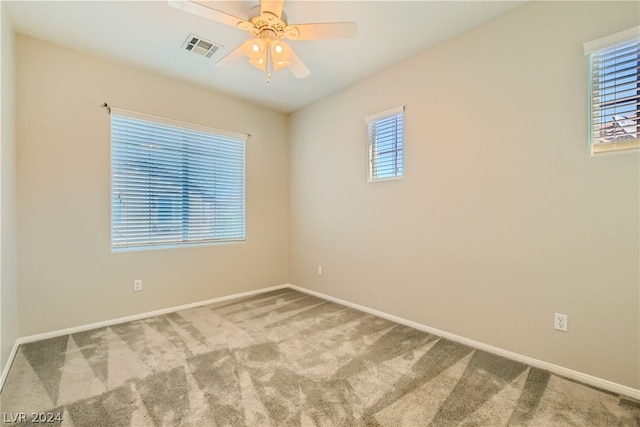 carpeted spare room featuring plenty of natural light and ceiling fan