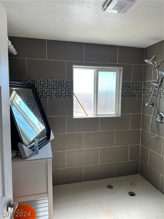 bathroom with a textured ceiling and a tile shower