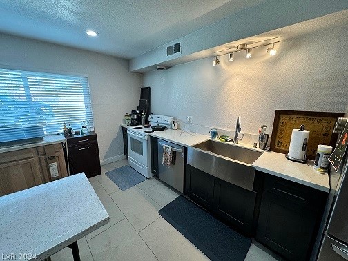 kitchen featuring light tile flooring, sink, electric range, dishwasher, and a textured ceiling