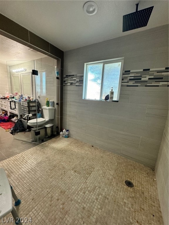 bathroom featuring tile walls, a textured ceiling, and tile flooring