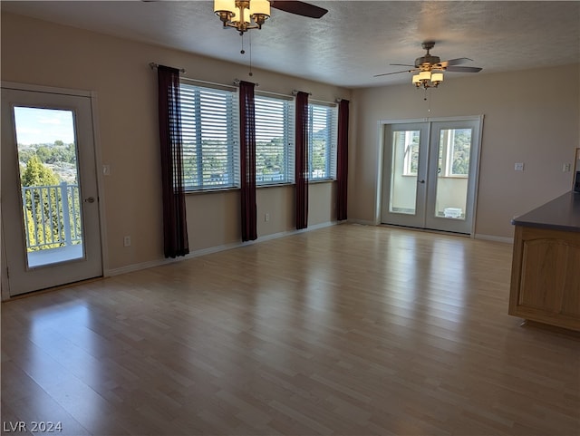 unfurnished room featuring ceiling fan, french doors, light hardwood / wood-style flooring, and a textured ceiling