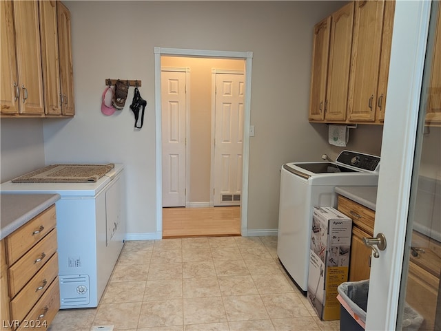 laundry area featuring independent washer and dryer, cabinets, and light tile flooring