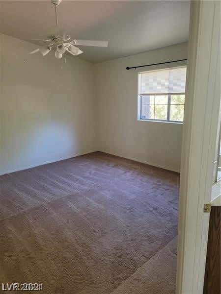 empty room featuring ceiling fan and dark carpet